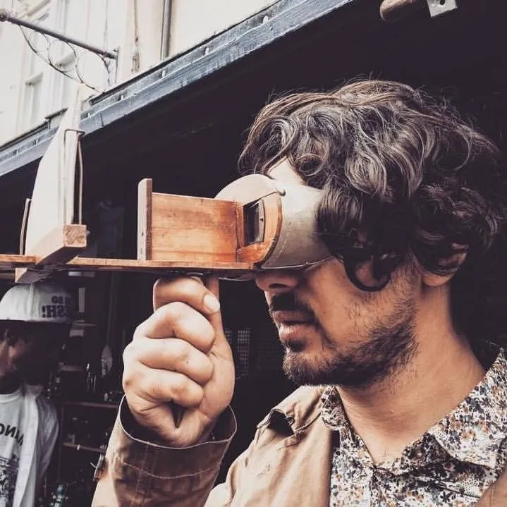 Ertu Muslu looking through a wooden director’s viewfinder